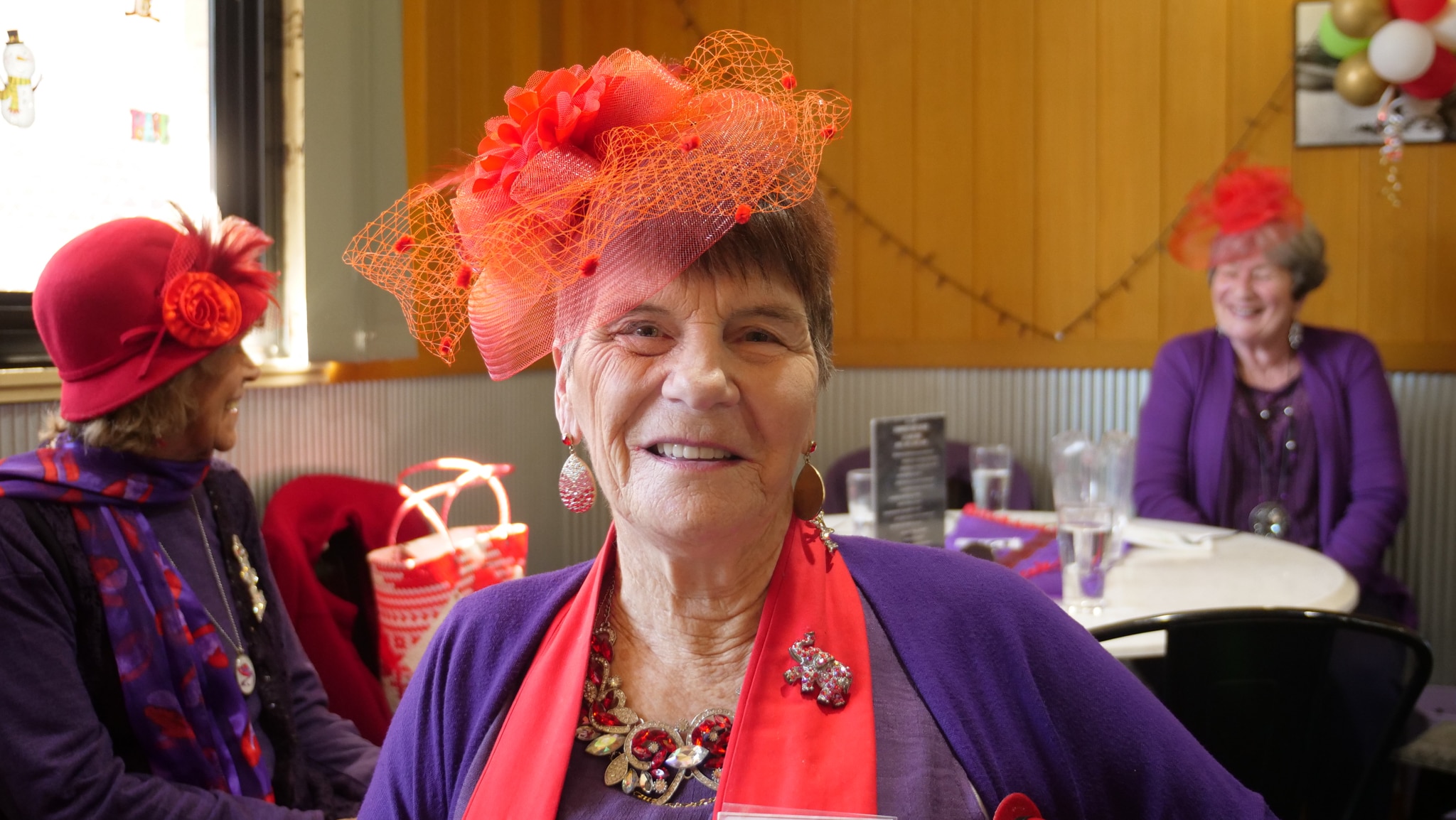 A seated woman wearing red and purple also wears a lot of bling