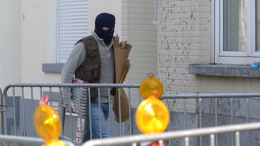A Belgian police officer arrives at the scene of an anti-terror raid