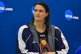 Lia Thomas looks off to one side wearing a jacket and holding a trophy to her chest