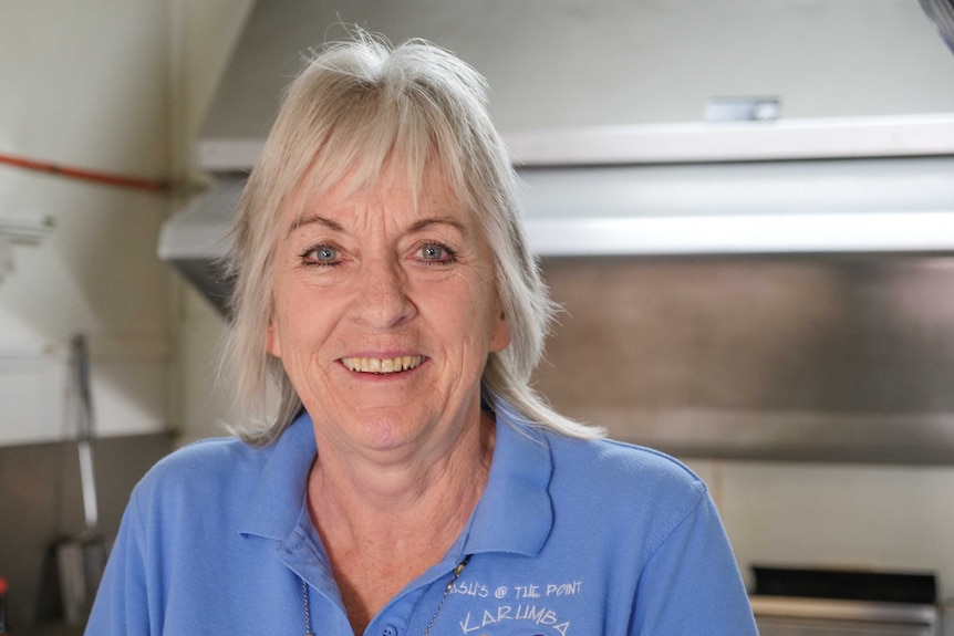 An image of an older woman with blonde hair and bright blue eyes smiling at the camera.