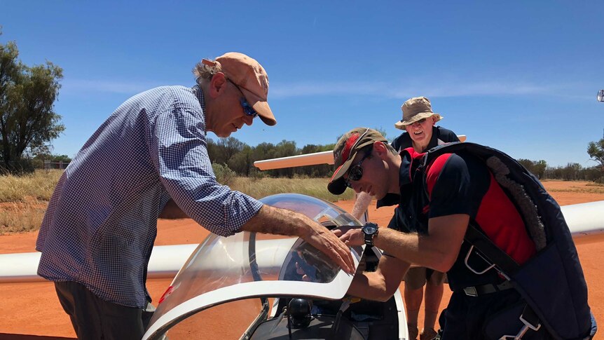 Three men inspect a glider plane in Alice Springs.