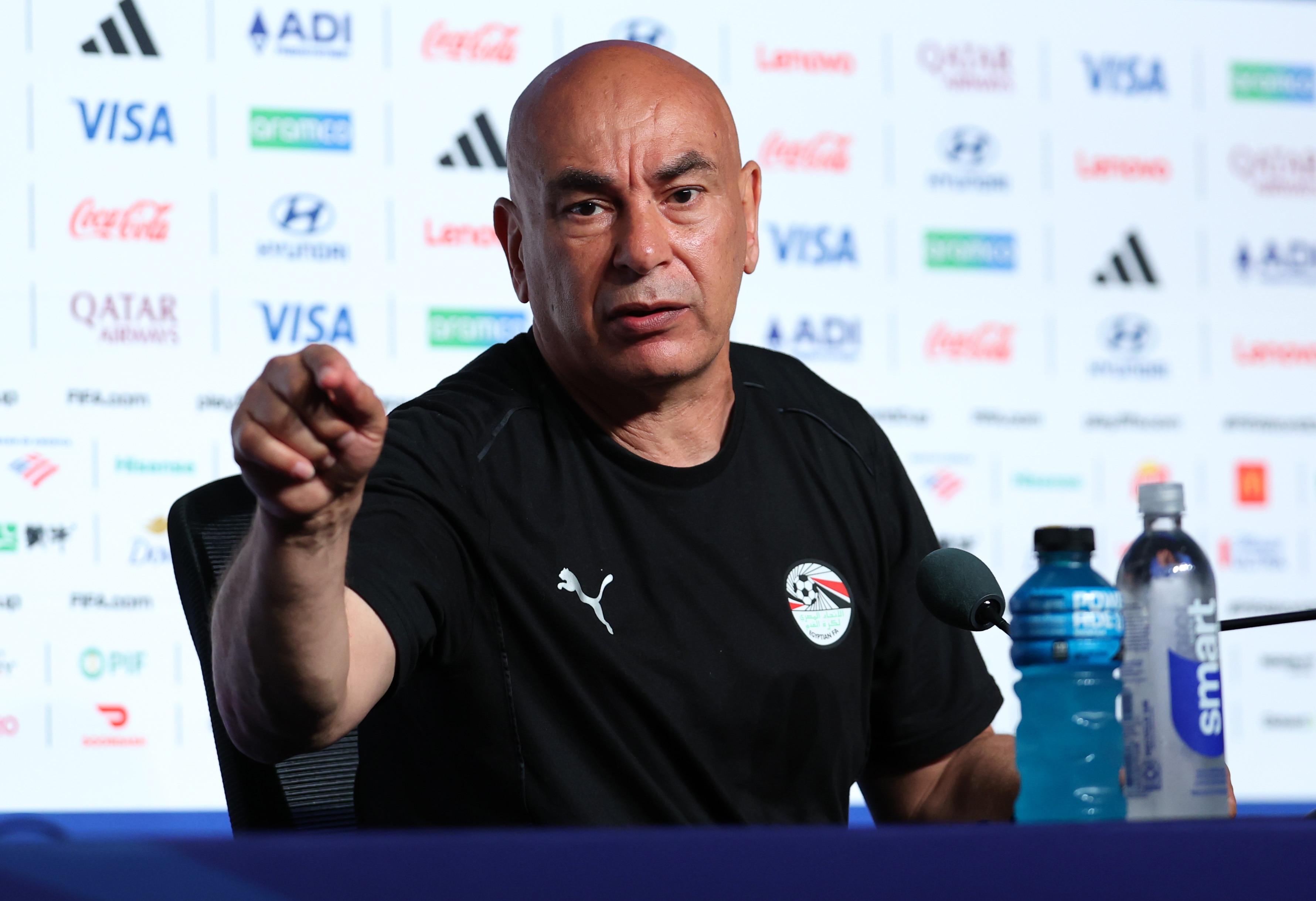 Hossam Hassan points towards something while speaking at a press conference