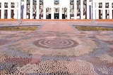 A huge dot-technique Indigenous artwork covers the paving in the forecourt of Parliament House.
