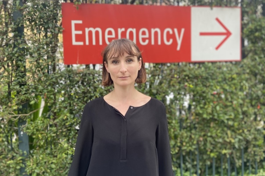 a woman standing in front of an emergency sign