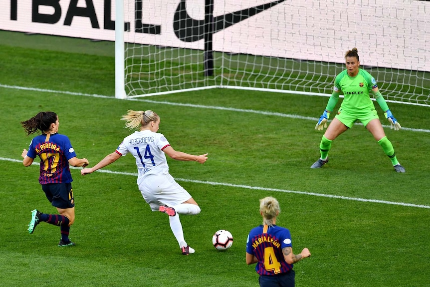 Ada Hegerberg strikes the ball close to goal while surrounded by defenders.