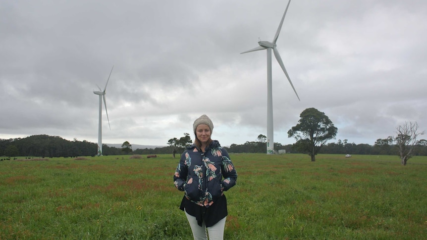 Taryn Lane from Hepburn Wind stands by two of the community-owned turbines at Daylesford, Victoria.