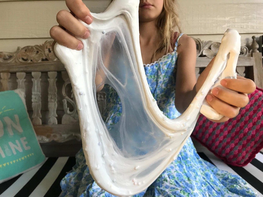 Young girl stretches a batch of slime.