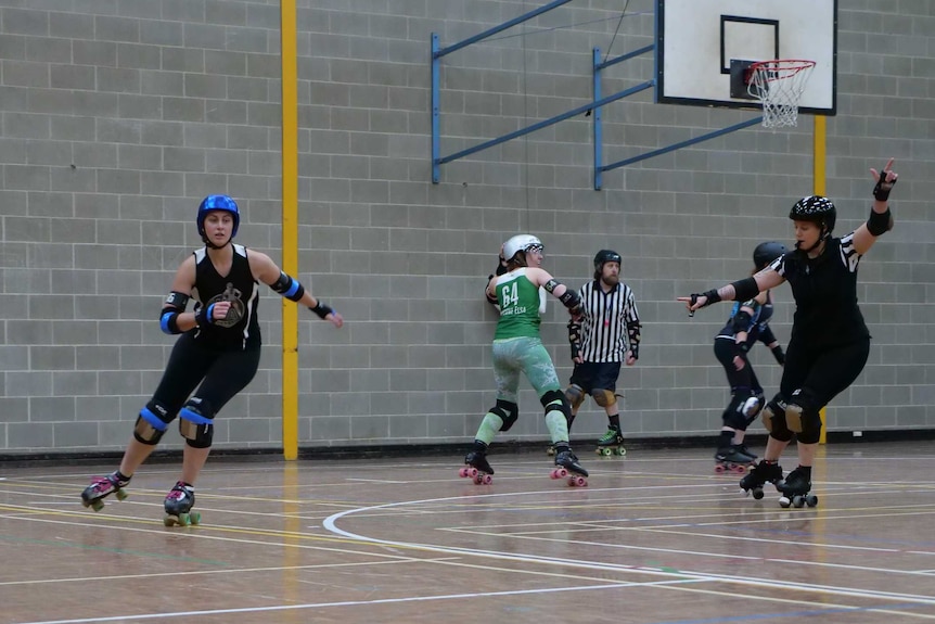 A skater makes their way around the court as a referee whistles and holds up her hand.