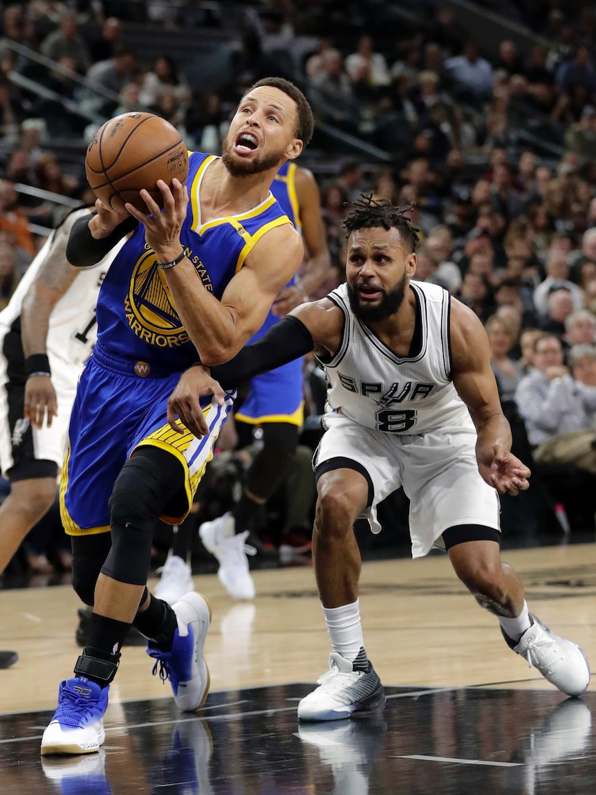 Steph Curry (L) drives past Patty Mills on his way to the basket in Game 4 in San Antonio.