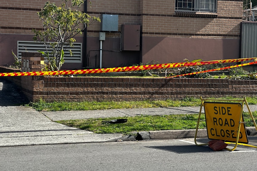 Red and yellow tape and a 'side road closed' sign