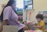 Ms McIntosh and her daughter playing on the floor of her room, surrounded by toys