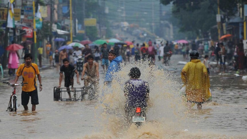 Residents commute along a flooded street in suburban Manila