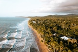 A drone shot of the ocean against a backdrop of rainforest