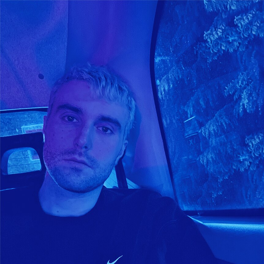 photo of fred again sitting in a car with a blue treatment over the photo