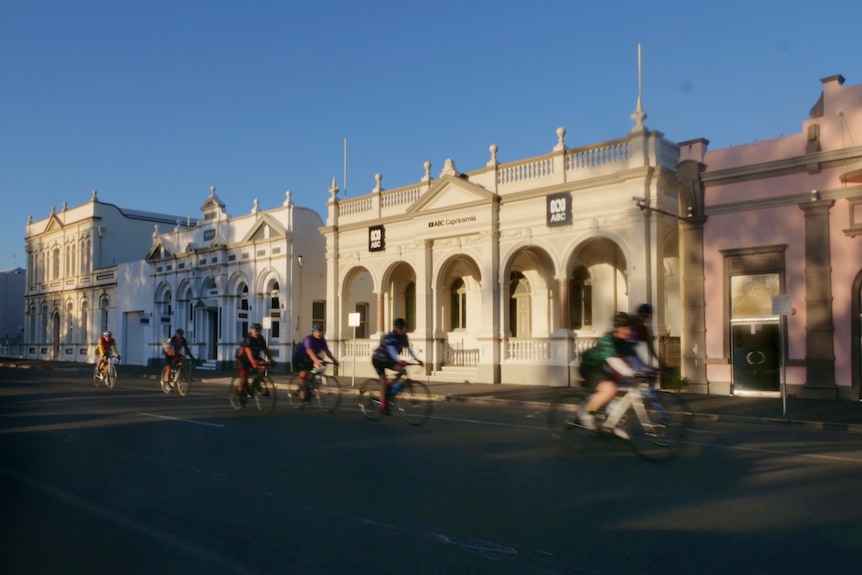 Cyclists ride past some heritage-listed buildings, including the ABC, on Quay St.