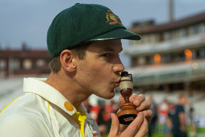 An Australian male cricketer kisses the Ashes urn in 2019.