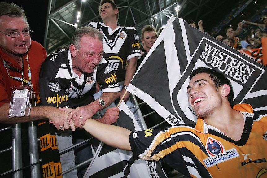 A man celebrates with fans after winning a grand final