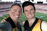 Guy Stayner with his son Zack in the stands with a crowded MCG in the background.