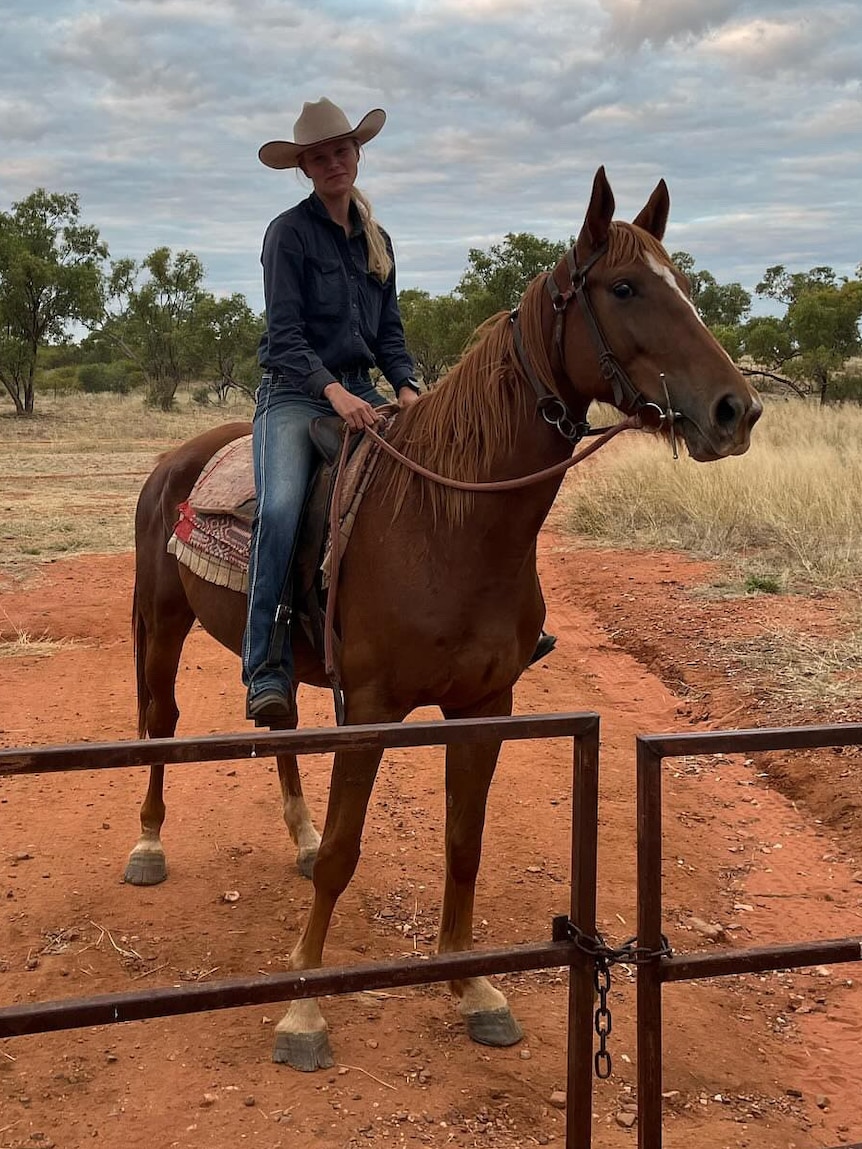 A blonde woman on horseback on a cattle property