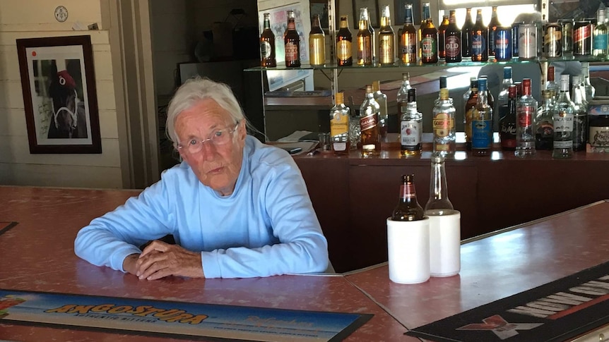 An elderly woman behind the bar in a pub