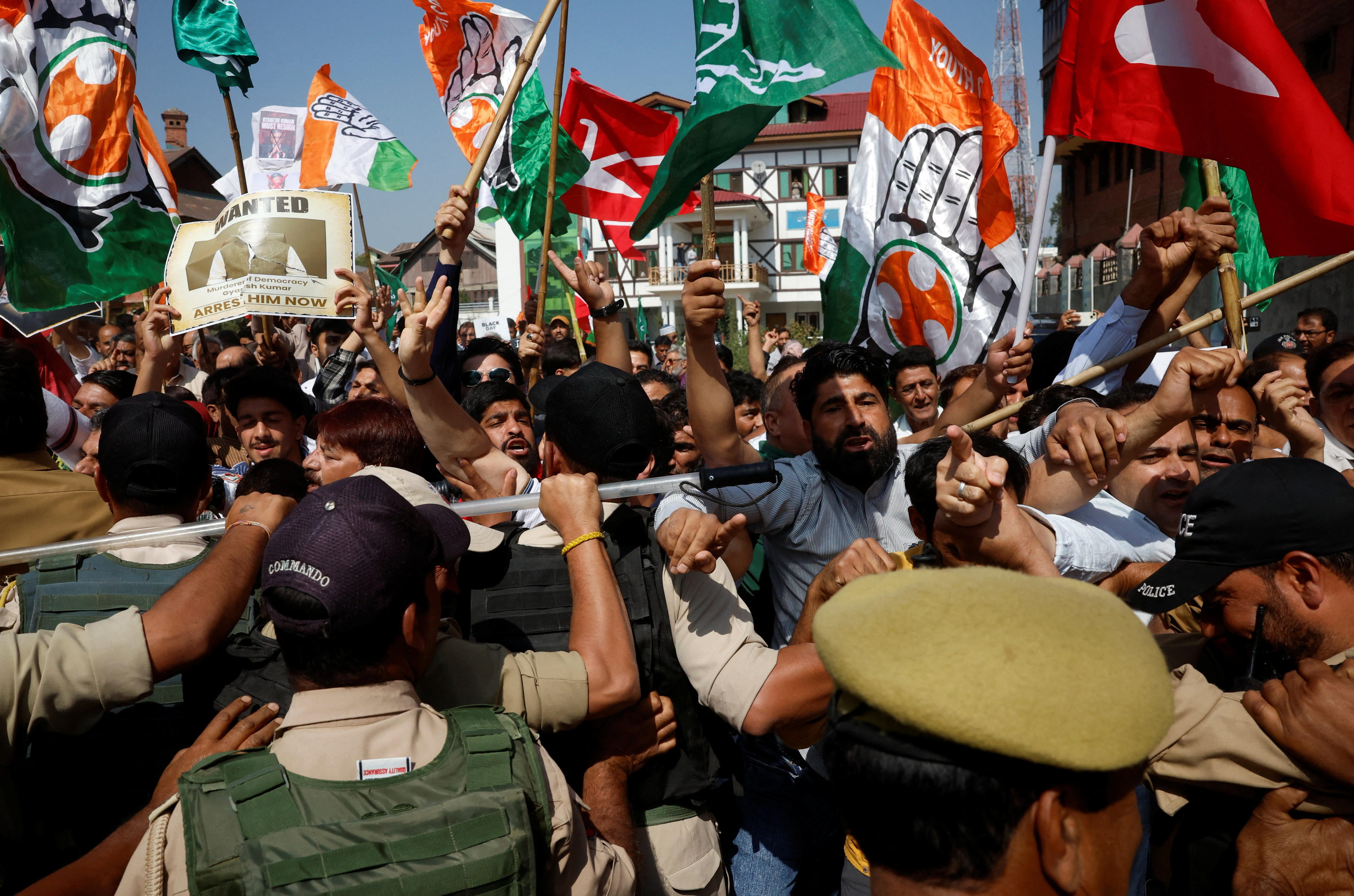 Police clash with a crowd of protesters holding flags and signs in a close-up shot