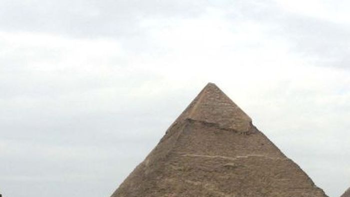 Tourists ride horses in front of the pyramids of Giza