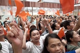 At least a hundred people wave Chinese flags as they look up during a packed demonstration at a mall.