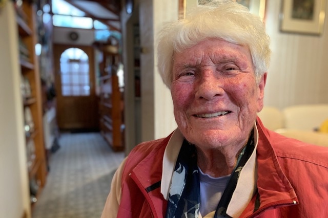 An older woman smiles in a head and shoulders shot