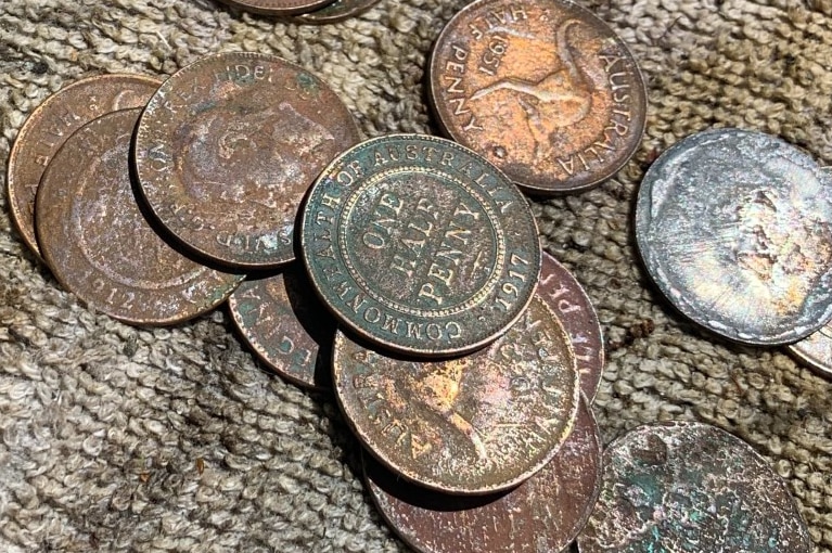 A collection of old bronze-coloured Australian coins on a dirty towel.