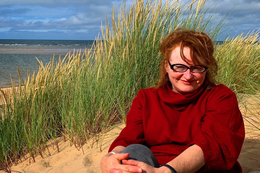 Fiona Gruber sitting on sand dunes on the Norfolk coast