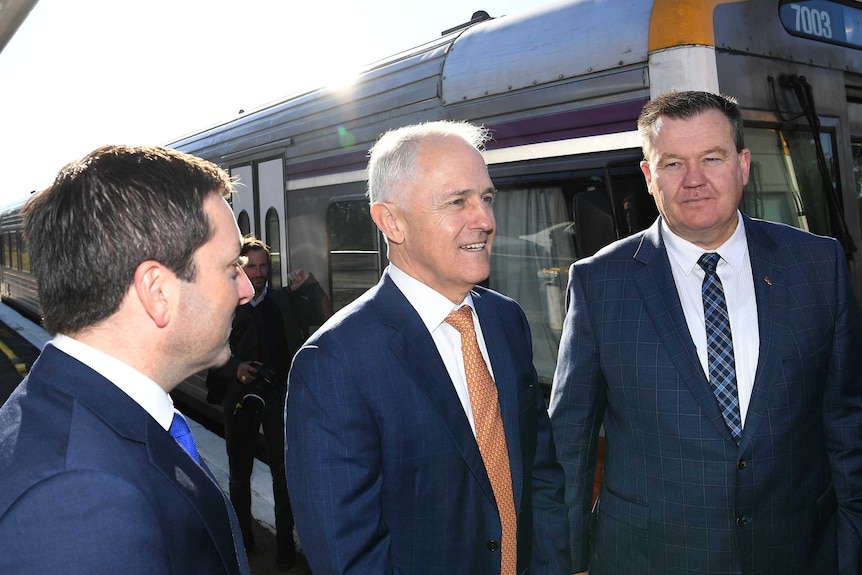 Matthew Guy, Malcolm Turnbull and Liberal candidate for Frankston Michael Michael Lamb stand on beside a train.