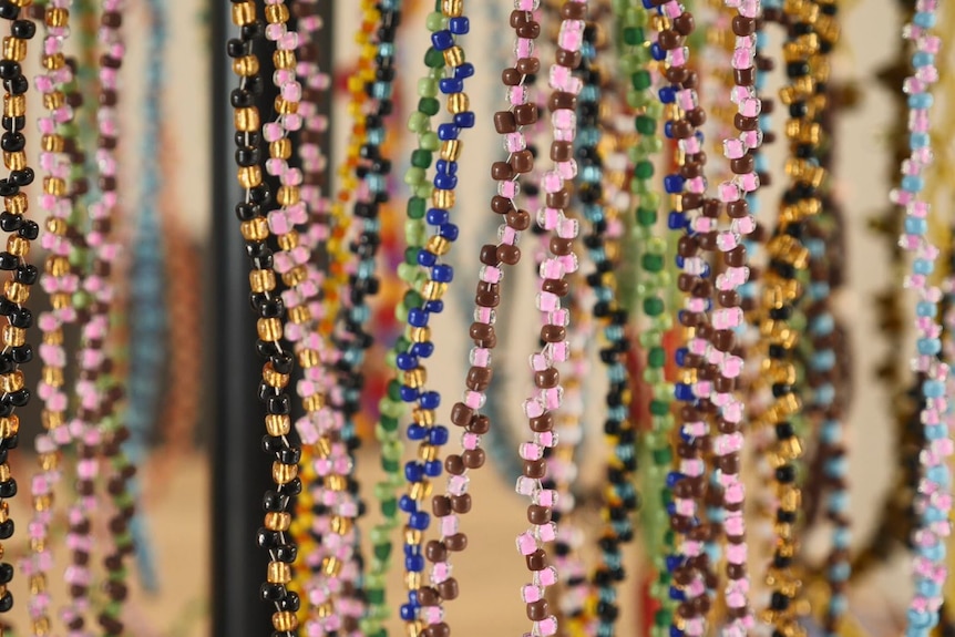 Colourful beaded jewellery hangs on a display rack.