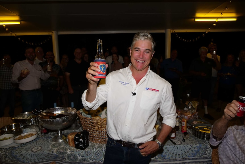 Man holds a beer smiling.