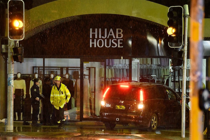 Emergency workers remove a car from a shop in the rain.