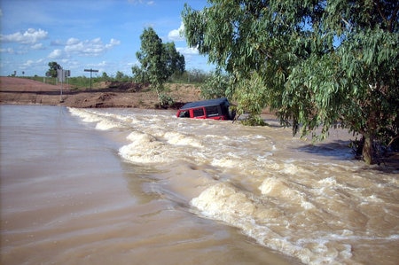A red car has been washed into rushing flood waters on the Torrens Creek - Aramac Road in western Queensland