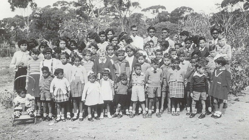 A black and white group photograph of mission children and some adults.