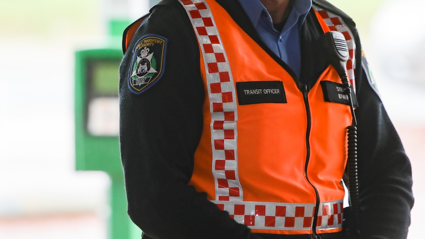 A man wearing a high-vis vest stands with his hands clasped.