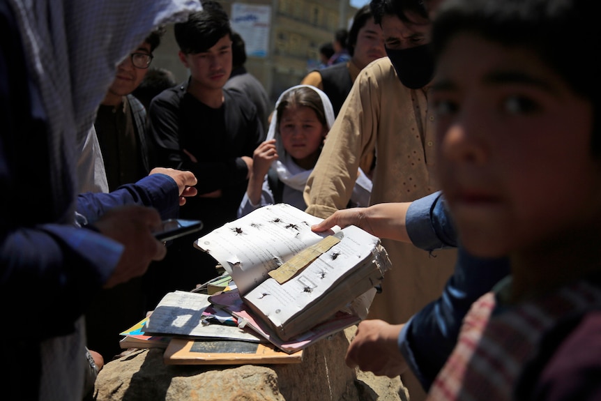 Afghans go through belongings of victims of a school bombing
