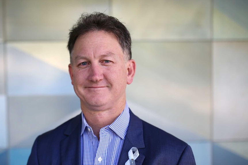 A headshot of Michael Gannon, wearing a blue jacket and white and blue shirt.