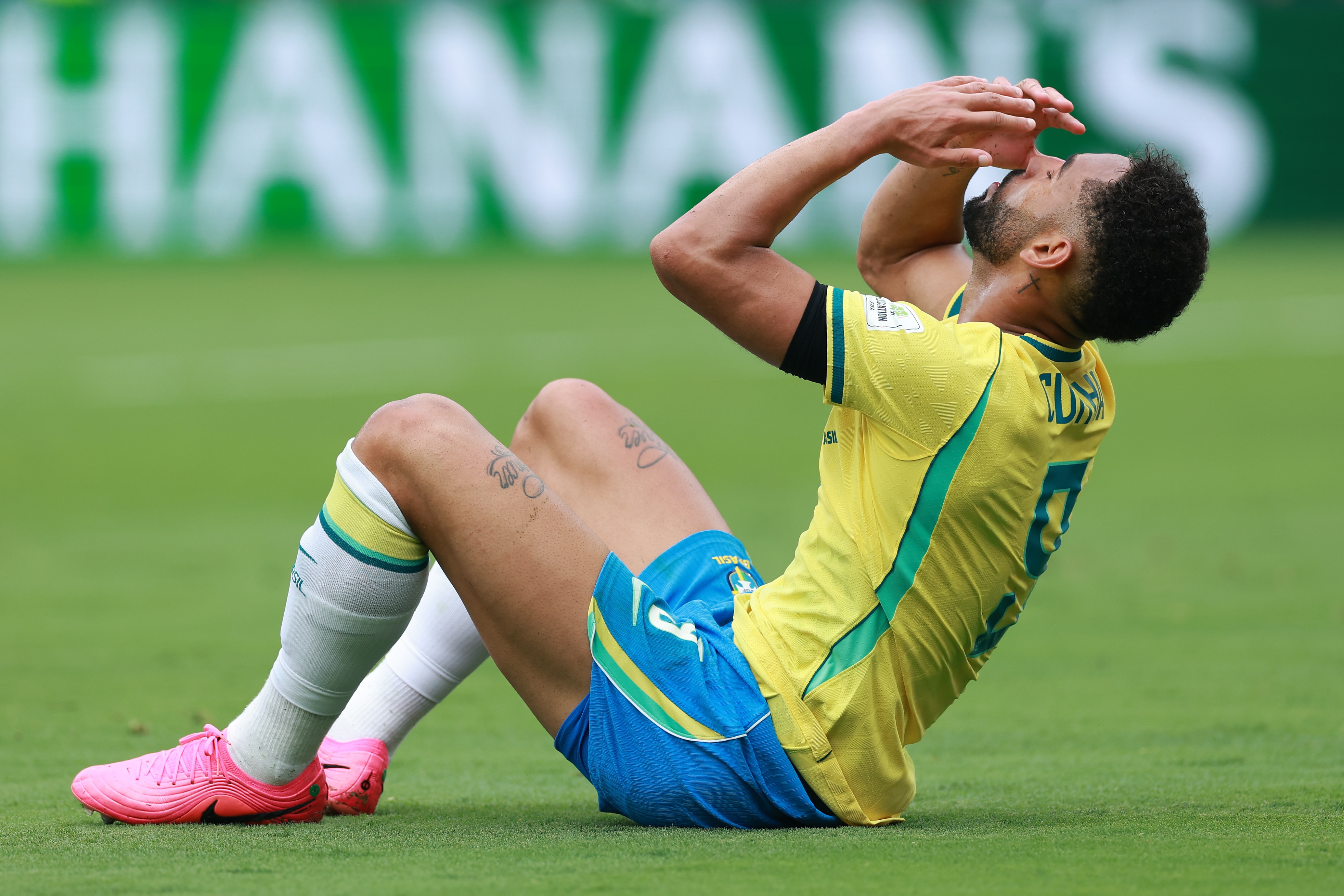 Matheus Cunha holds his hands on his head while sitting on the grass
