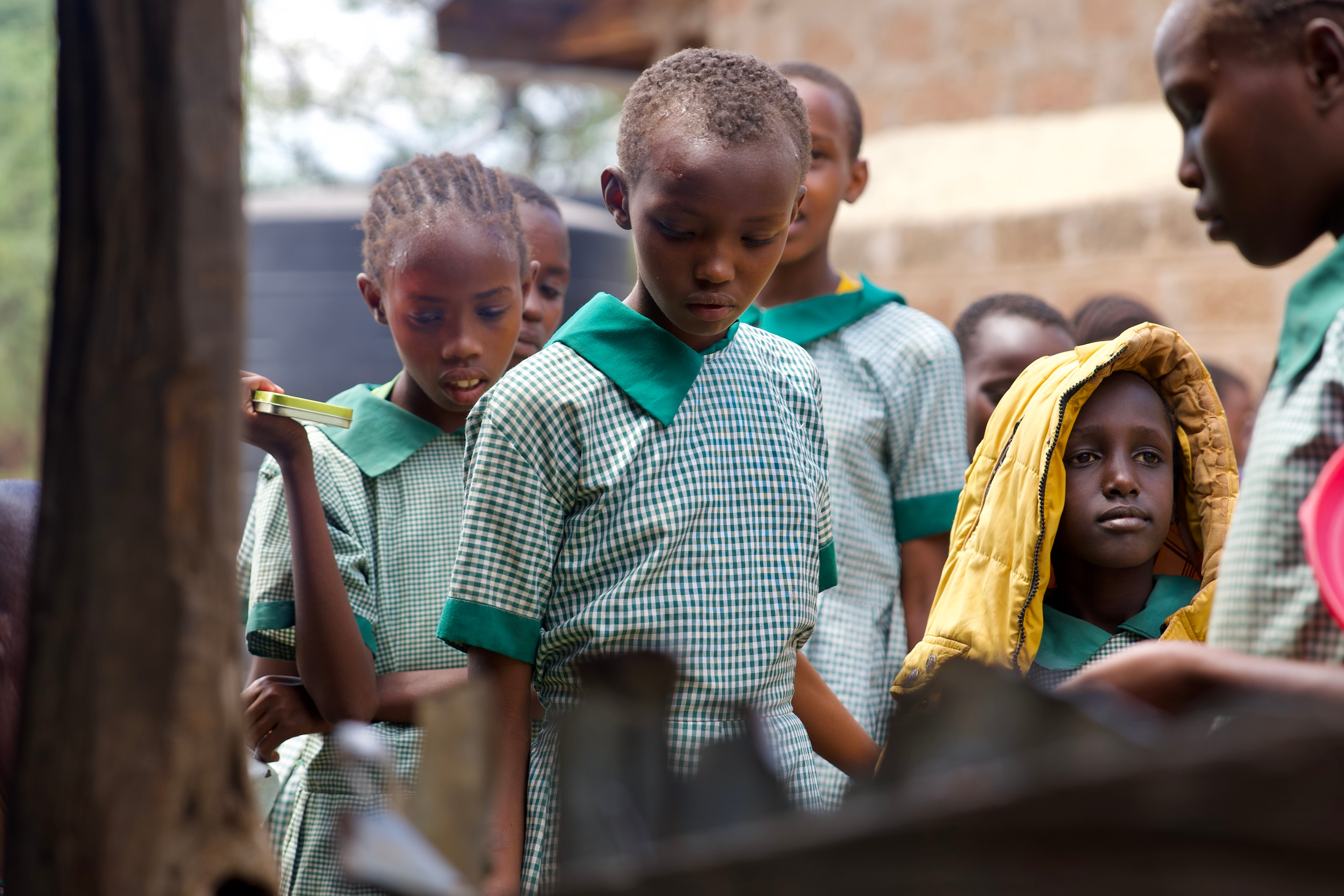 A group of Kenyan school students line up for porridge. 