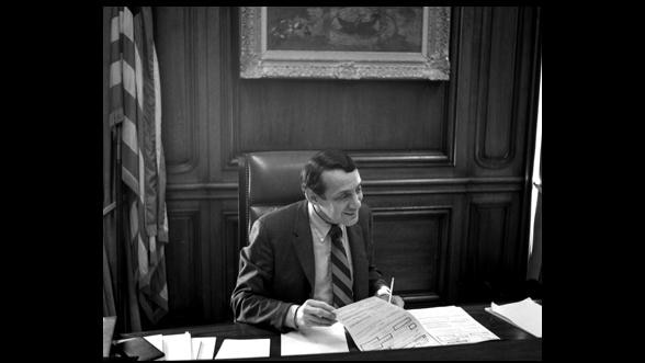 Harvey Milk turns a page at a desk in the San Francisco mayor's office.