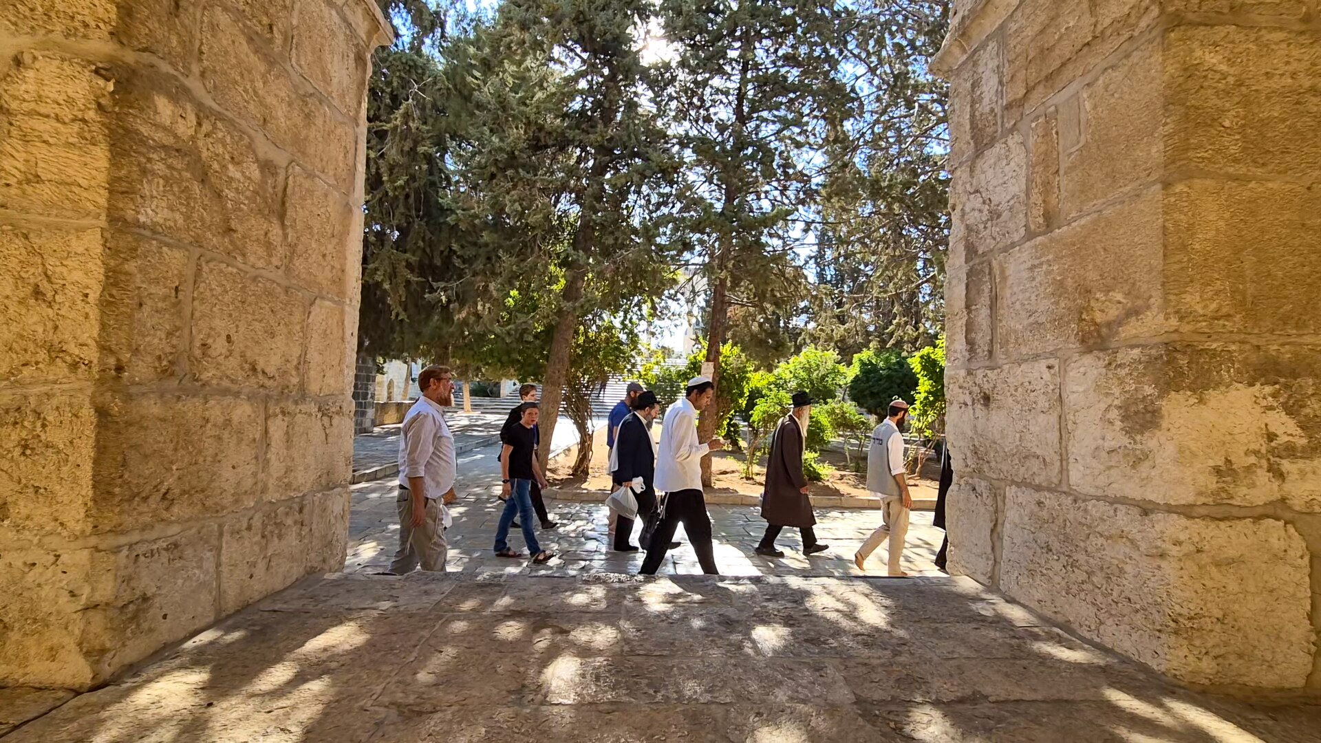 Yehuda Glick walks with a group of Jews past a portal in a thick stone wall.
