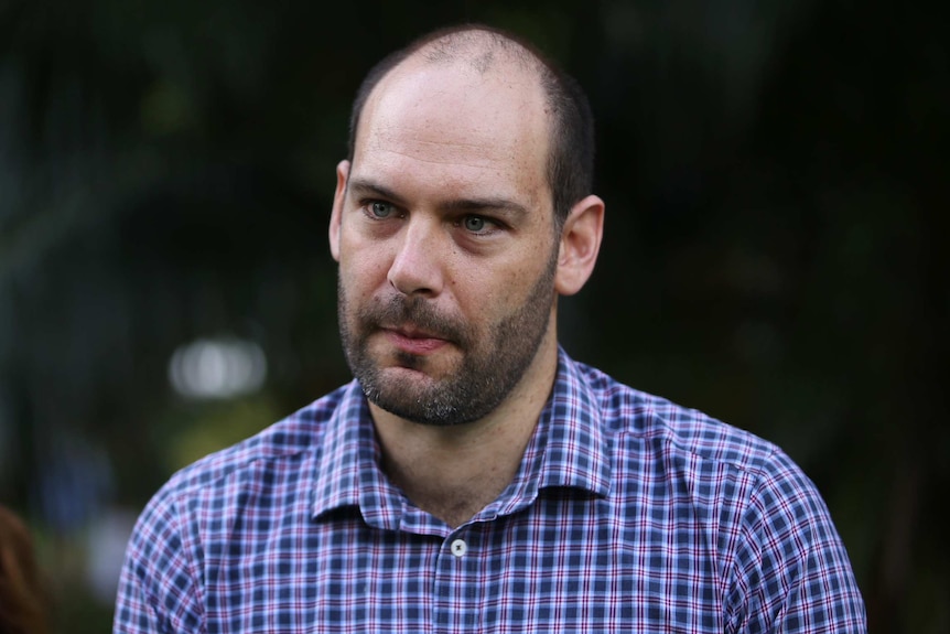 A head shot of a man wearing a checked shirt.