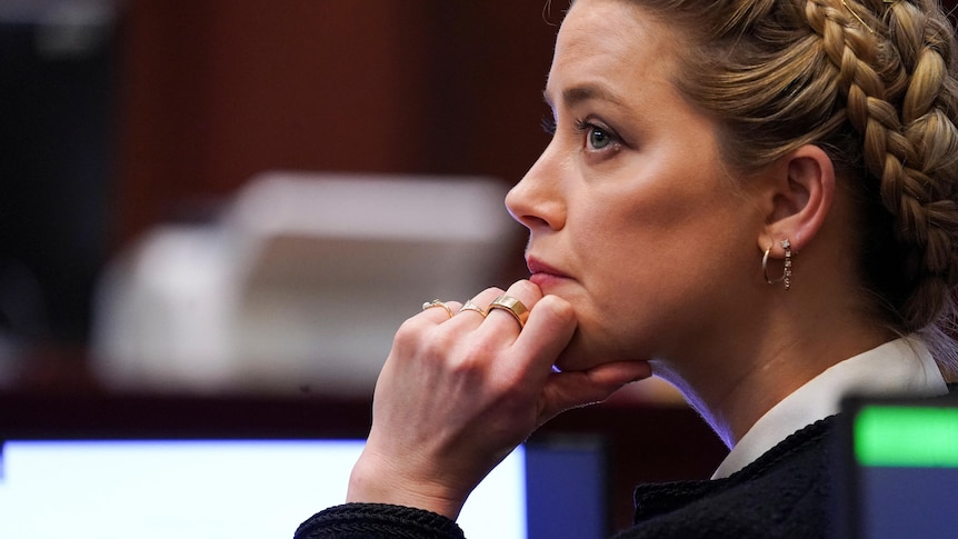 side view of Amber Heard in which she has her hand to her chin and hair braided and pulled back