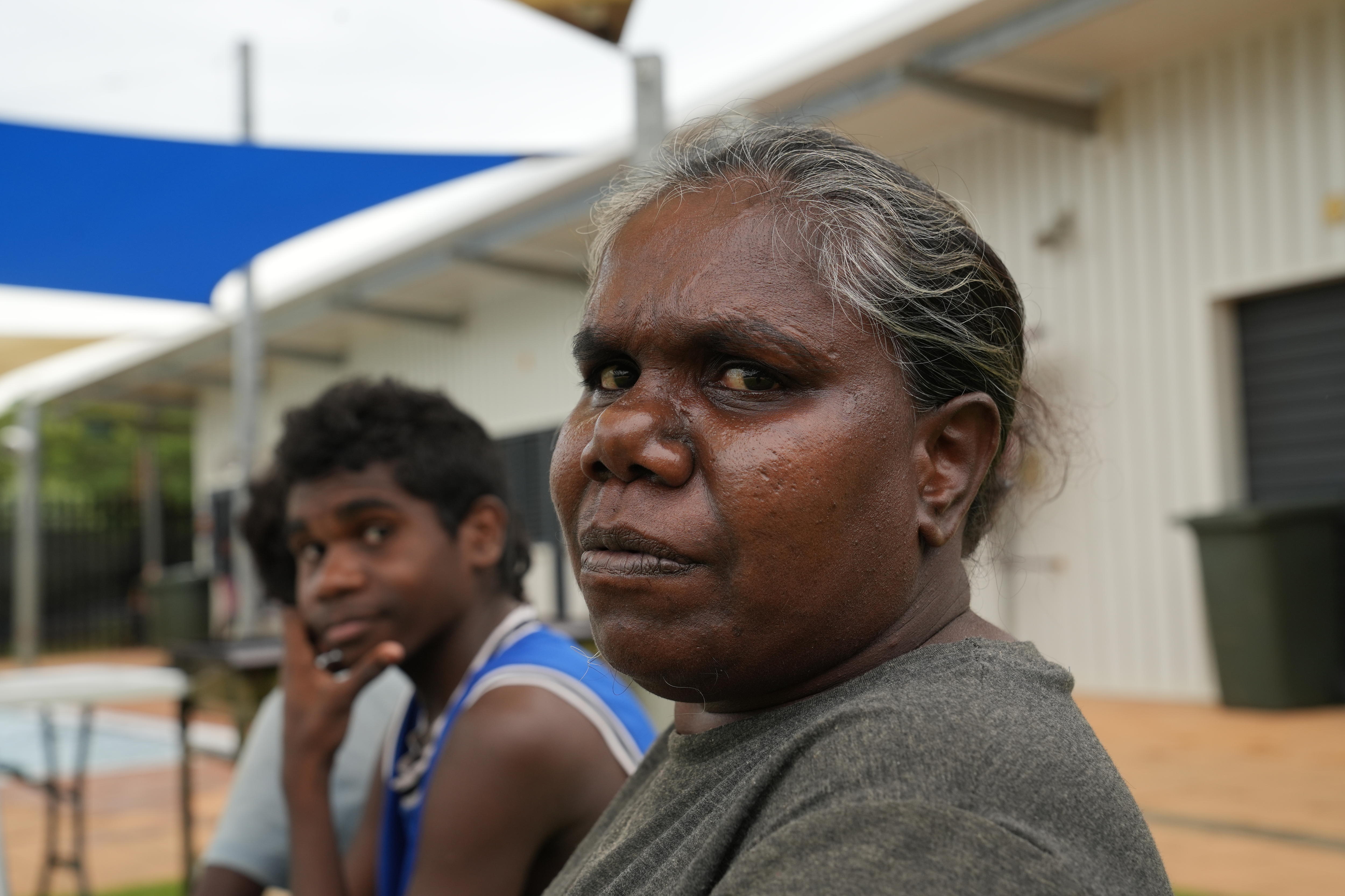 Indigenous woman with grey hair sitting with children