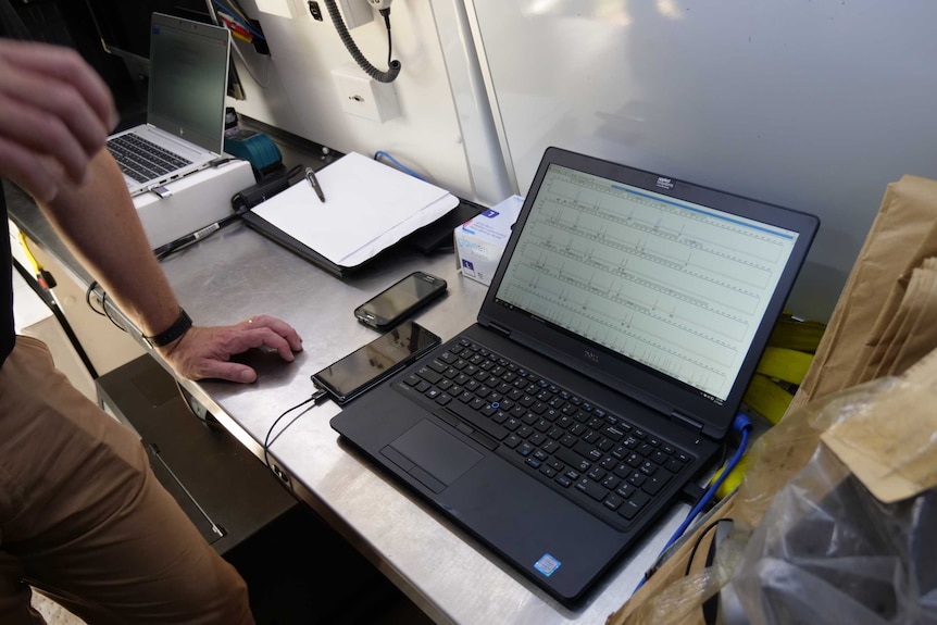 A laptop displaying DNA profiles rests on the table inside a mobile laboratory.