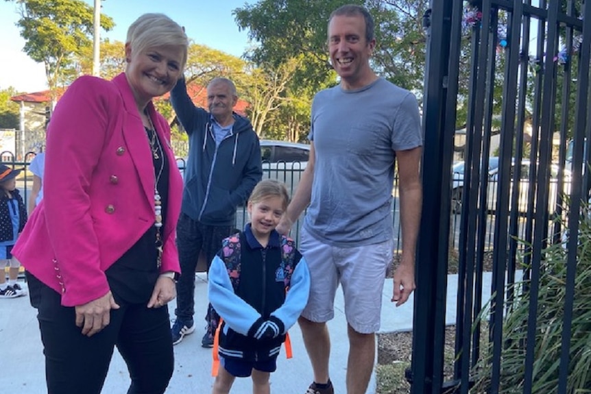 A father and daughter with a school teacher at the school gate