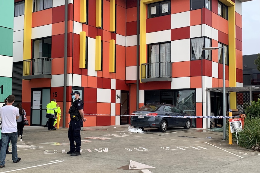 A colourful apartment building with police outside.