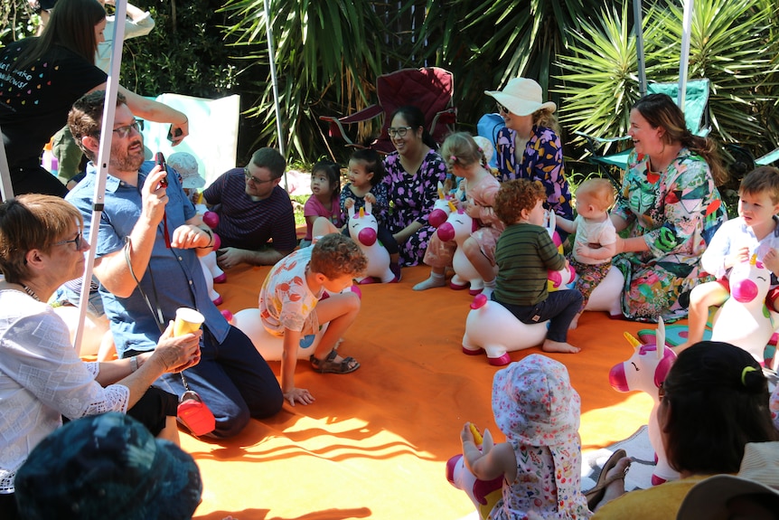 A group of parents and children sit in a circle.